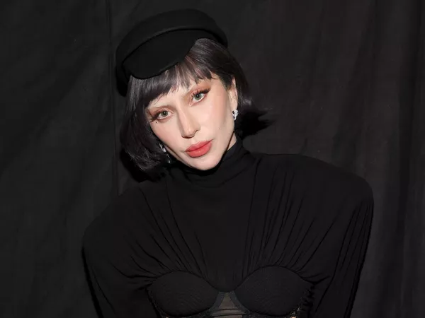 Lady Gaga wears a black semi-structured dress and brimmed hat
